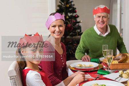Smiling extended family in party hat at dinner table at home in the living room