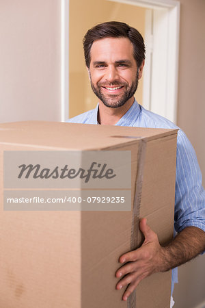 Happy man carrying moving box in his new home