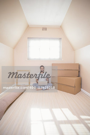 Happy man using laptop surrounded by boxes in his new home