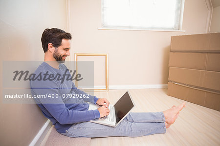 Casual man using laptop after moving in in his new home