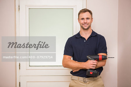 Construction worker holding power tool with arms crossed in a new house