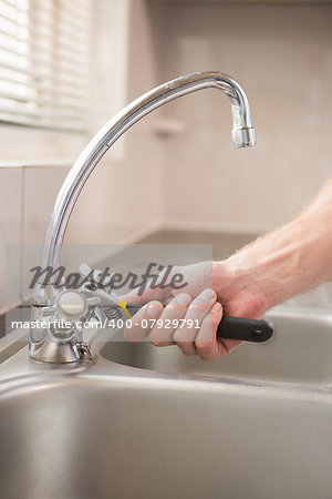 Man fixing tap with pliers at home in the kitchen