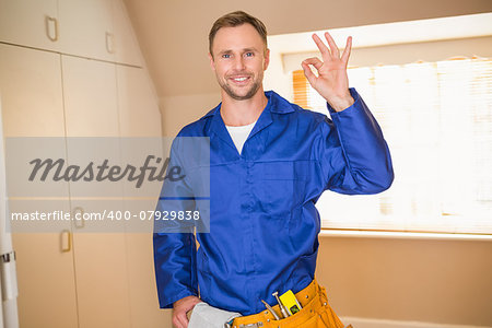 Handyman smiling at camera in tool belt in a new house