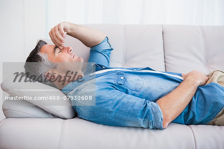 Man with grey hair relaxing on the couch at home in the living room