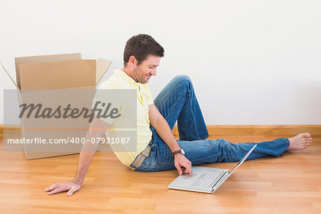 Casual man sitting on floor using laptop at home in the living room