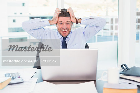 Smiling businessman  taking his head in his office