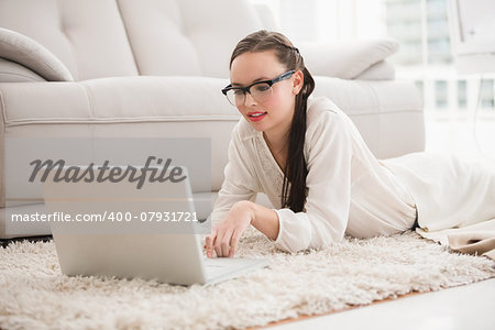 Pretty brunette using laptop on the floor at home in the living room