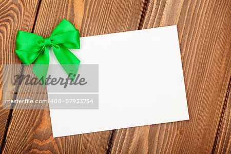 Valentines day greeting card with green bow over wooden background