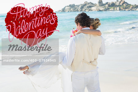 Handsome groom carrying his beautiful wife out to the water against happy valentines day