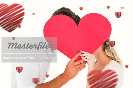 Attractive young couple kissing behind large heart against hearts