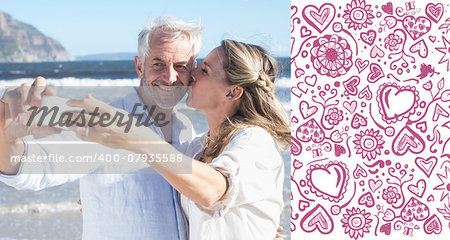 Married couple at the beach together taking a selfie against valentines pattern
