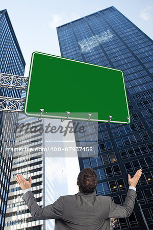 Businessman posing with arms raised against low angle view of skyscrapers