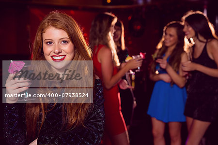 Pretty redhead drinking a cocktail at the nightclub