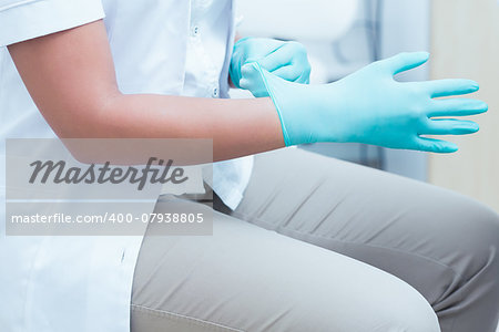 Close up mid section of female dentist wearing surgical glove