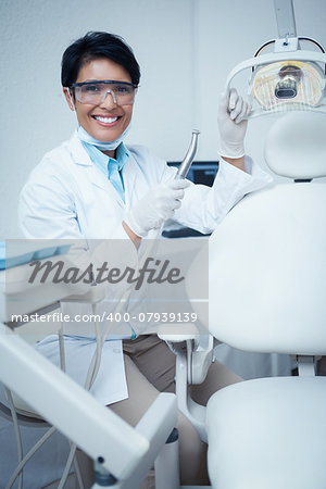 Portrait of smiling young female dentist holding dental tool