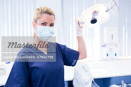 Dentist in mask holding light at the dental clinic