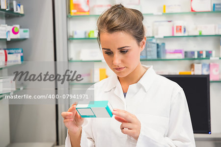 Junior pharmacist reading medicine box at the hospital pharmacy