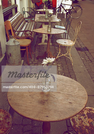 Empty Sidewalk Cafe with Wooden Tables and Old Chairs on Cobblestone Street in Copenhagen Outdoors