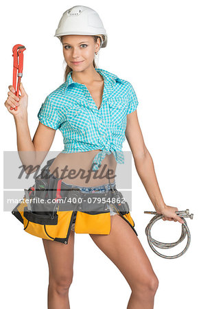 Pretty girl in helmet, shorts, shirt and tool belt with tools holding flexible hose and wrench. Isolated over white background