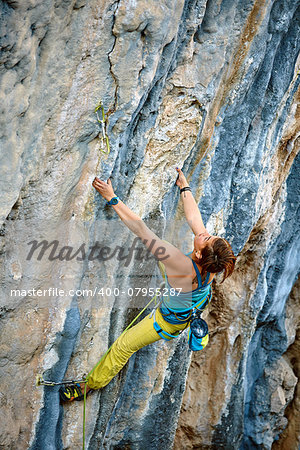 female rock climber climbs on a rocky wall