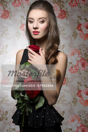 Young, beautiful, bright, elegant girl in black dress is holding valentines present like rose and heart. Her makeup is perfect.