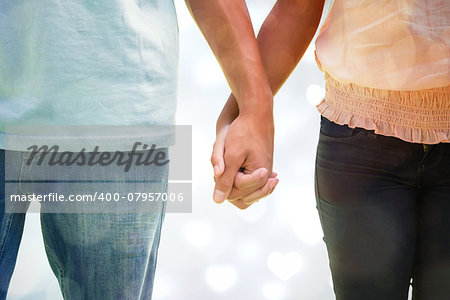 Young couple holding hands in the park against valentines heart design