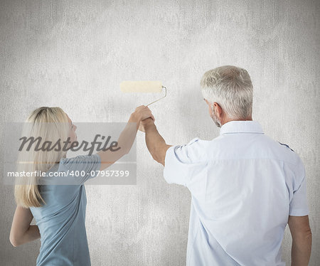 Happy couple painting wall with roller against weathered surface