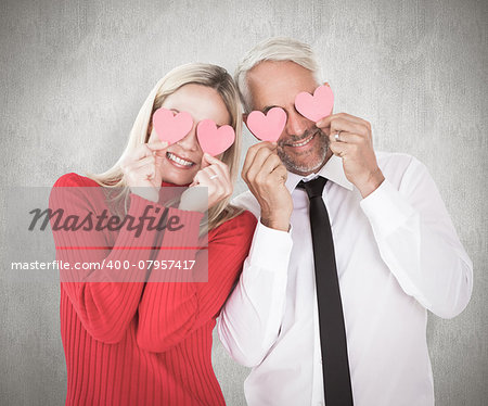 Silly couple holding hearts over their eyes against weathered surface