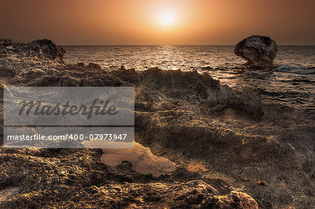 sunset over the sea with rocks in foreground