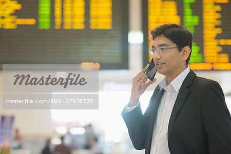 Asian Indian Business man on the phone during his business travel, at the airport .