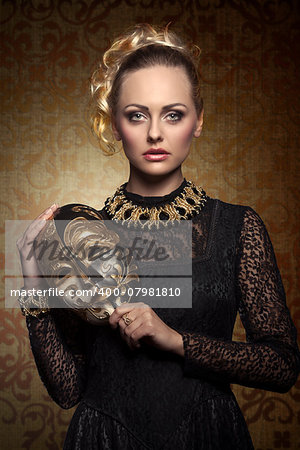 carnival portrait of blonde woman with aristocratic antique lady mask, elegant lace dress and baroque jewellery. Venetian mask in the hand