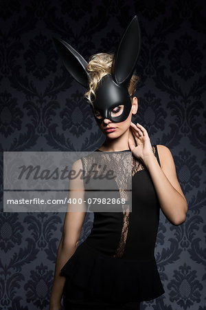 Sexy, beautiful, charming, blonde woamn in black rabbit mask and elegant black dress.
