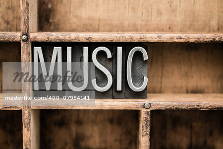 The word "MUSIC" written in vintage metal letterpress type in a wooden drawer with dividers.