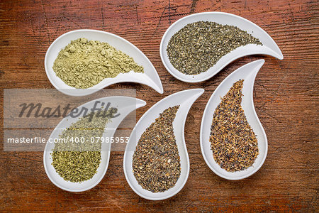 teardrop shaped bowls of seaweed diet supplements (bladderwrack, sea lettuce, kelp, wakame and Irish moss) on a grunge wood background