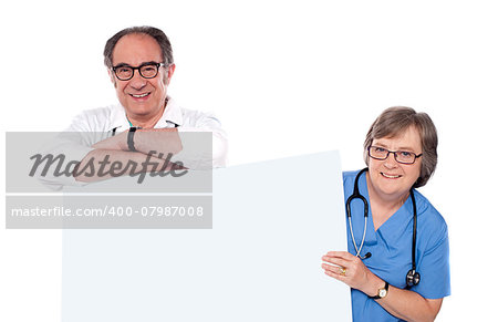 Two matured doctors holding white banner ad. All on white background