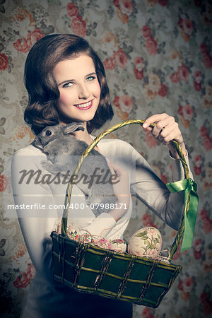 funny easter shoot of smiling vintage girl with colorful eggs in basket and fluffy rabbit