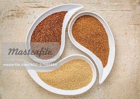 three tiny gluten free grains - kaniwa, amaranth and teff on teardrop shaped bowls against white painted rustic wood