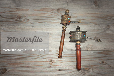 Tibetan prayer wheel or mani wheel on old wooden background with copy space, dramatic light in vintage tone.
