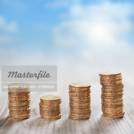 Coins stack in row on wooden background, financial concept. Focus on foreground with blur blue sky background.