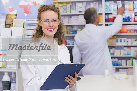 Pharmacist writing on clipboard at the hospital pharmacy