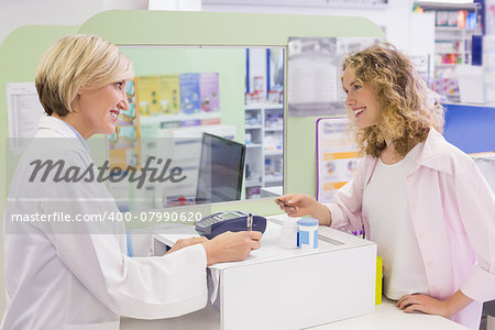 Pharmacist writing prescription in front of a customer in the pharmacy