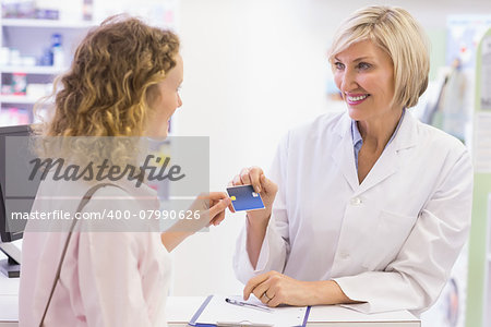 Pharmacist giving credit card to costumer at pharmacy