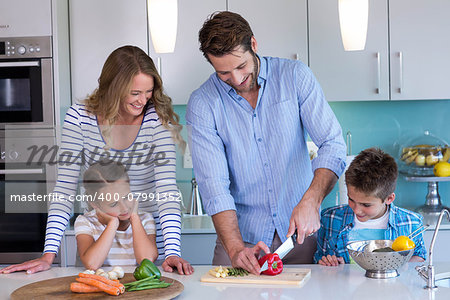 Happy family preparing vegetables together at home in the kitchen