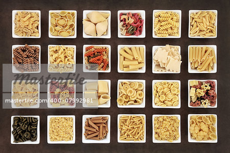 Large italian pasta dried food collection in square bowls over brown lokta paper background.