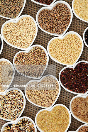 Grain and cereal food selection in heart shaped porcelain bowls over hessian background.