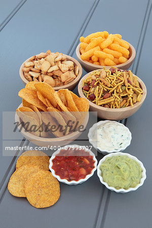 Savoury snack and dip party food selection in wooden bowls and porcelain dishes.