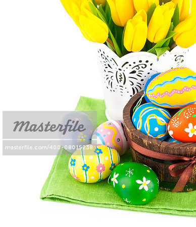 Easter eggs in basket with yellow tulips. Isolated on white background