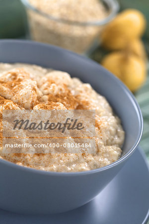 Bowl of cooked oatmeal porridge mixed with powdered maca or Peruvian ginseng (lat. Lepidium meyenii) with cinnamon on top, maca powder and maca roots in the back (Selective Focus, Focus in the middle of the oatmeal porridge)