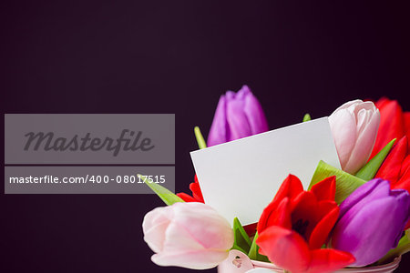 Bunch of tulips and white card on black background