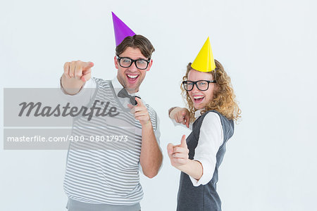 Happy geeky hipster couple dancing with party hat on white background